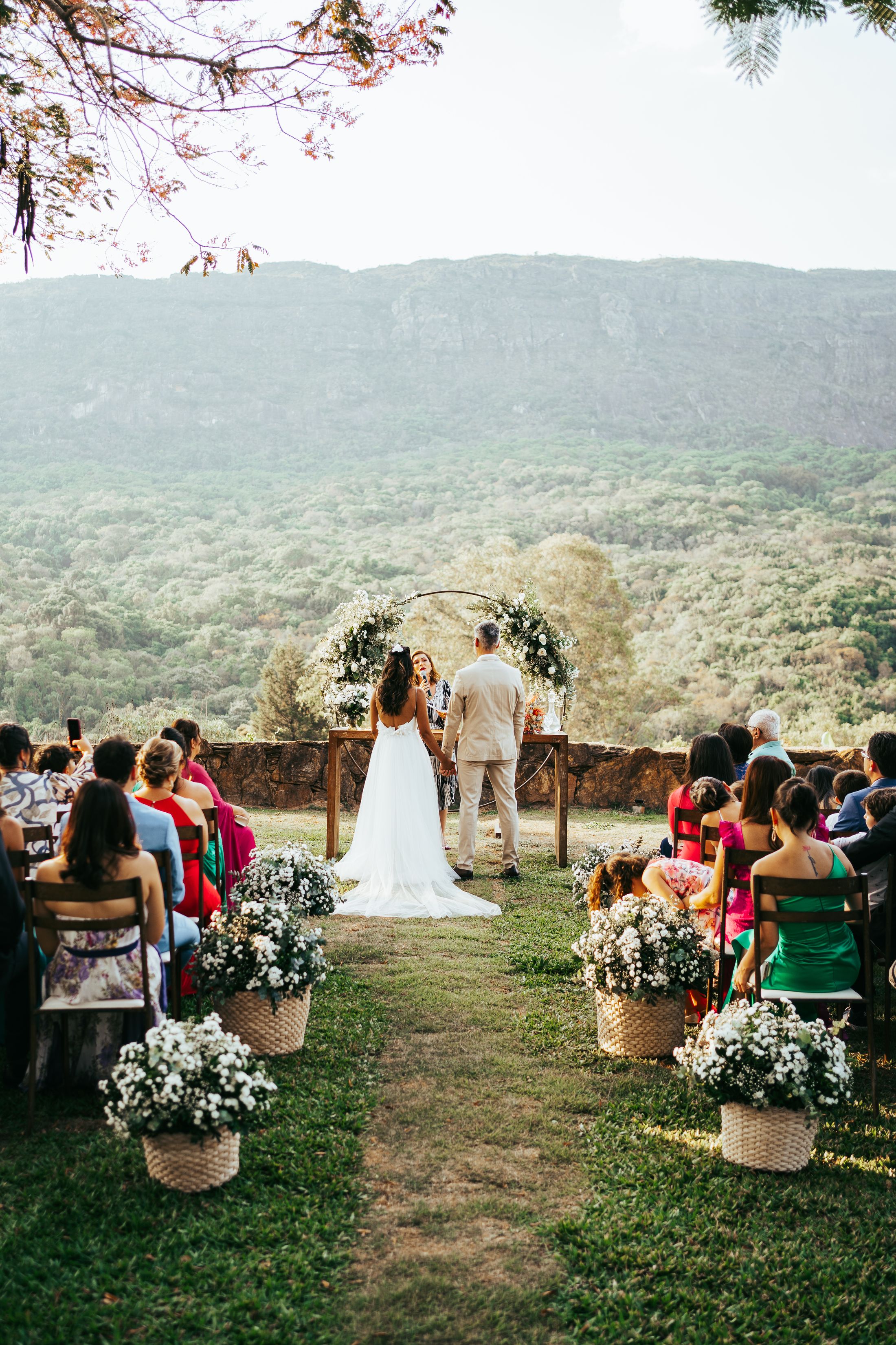 A couple exchanging vows outdoors with mountains beyond the ceremony