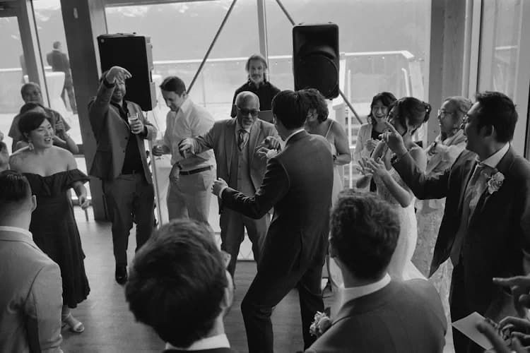 Editorial image of a wedding DJ with a full dance floor in a mountain-style reception setting
